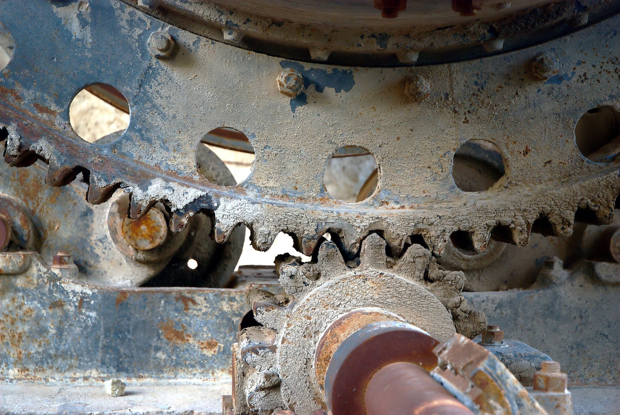 heavy old gears ruined by rust, wear, and concrete stuck in the teeth