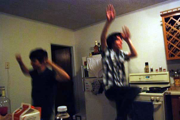 Two young men dancing exuberantly in the kitchen of a student apartment; a blurry moment of exultation