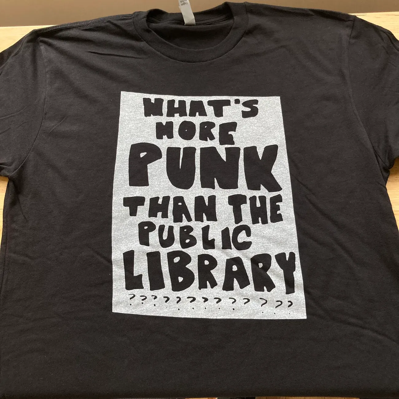Black t-shirt with the printed message: WHAT'S MORE PUNK THAN THE PUBLIC LIBRARY???????