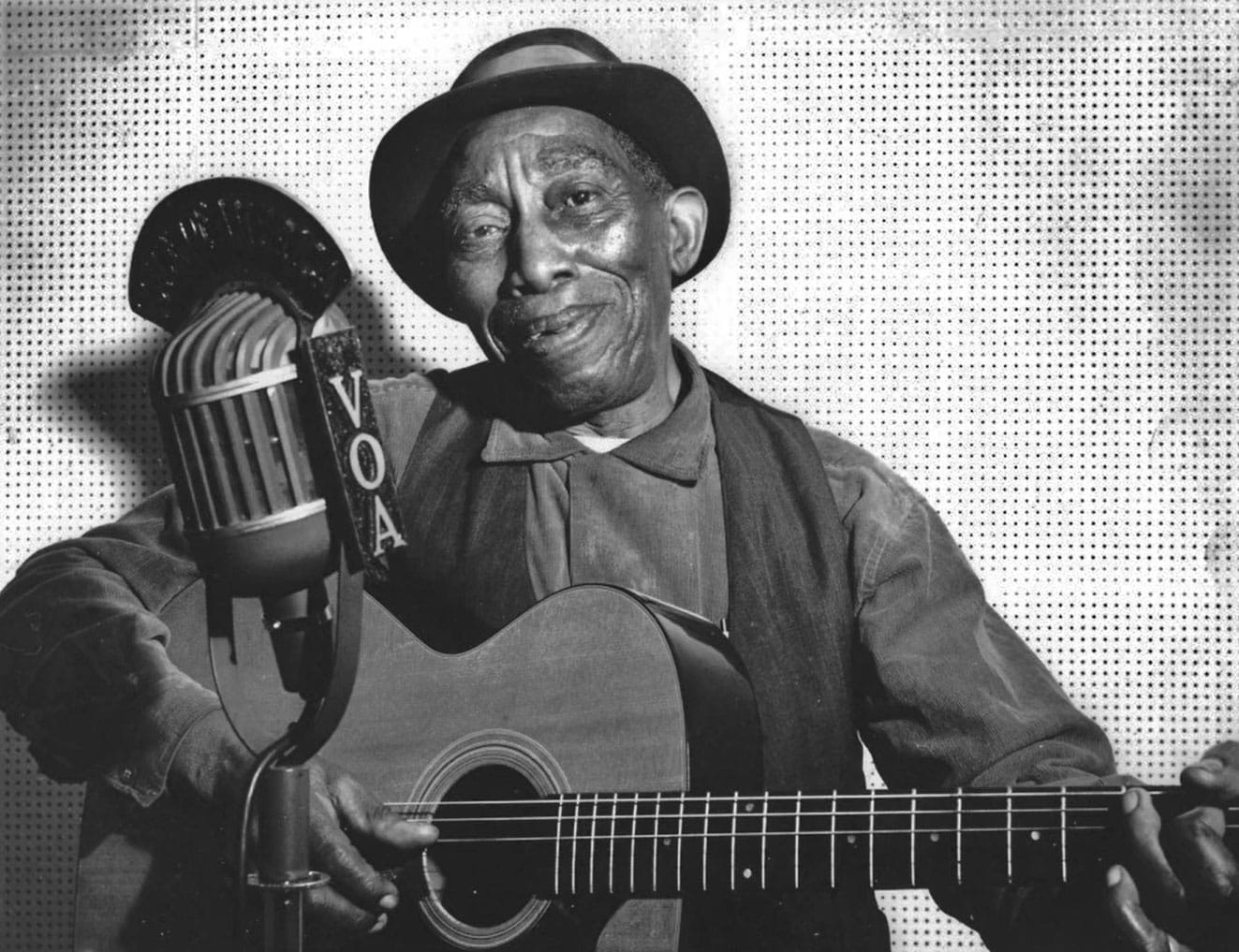 Mississippi John Hurt, pictured playing guitar in a VOA radio session