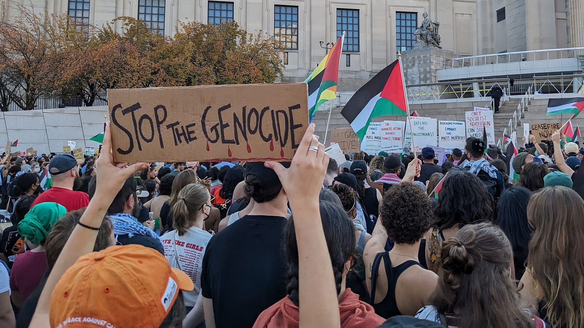 A pro-Palestine rally in Brooklyn, New York, on October 28, 2023; a hand-lettered sign reads "Stop the Genocide"