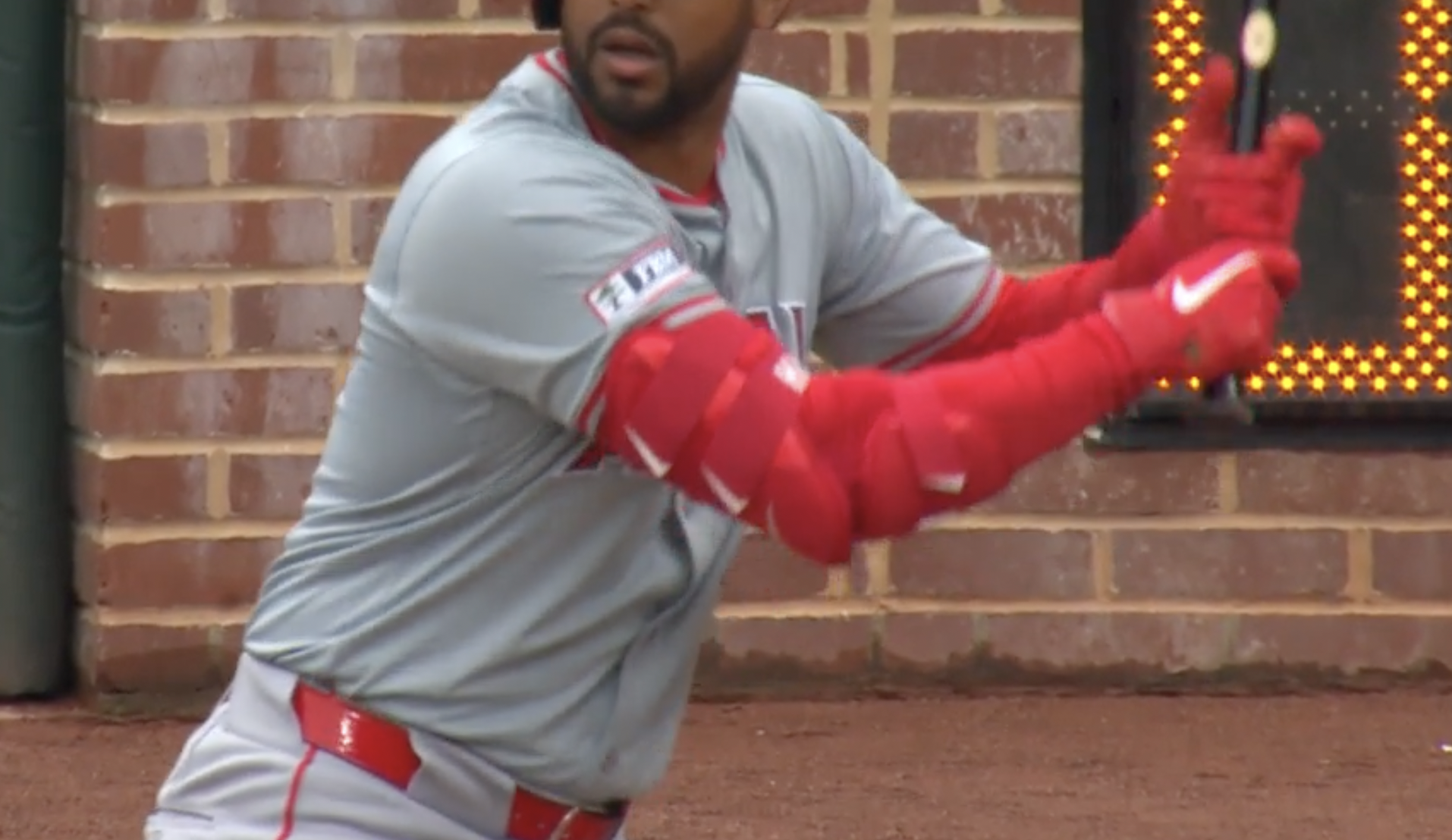 close up on a baseball player ready to swing. he's wearing red sleeves with red elbow guards on top