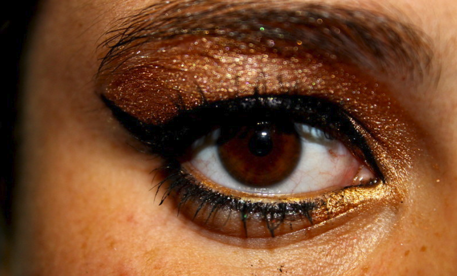 Close up on an eye with artfully applied eyeshadow and thick black winged eyeliner