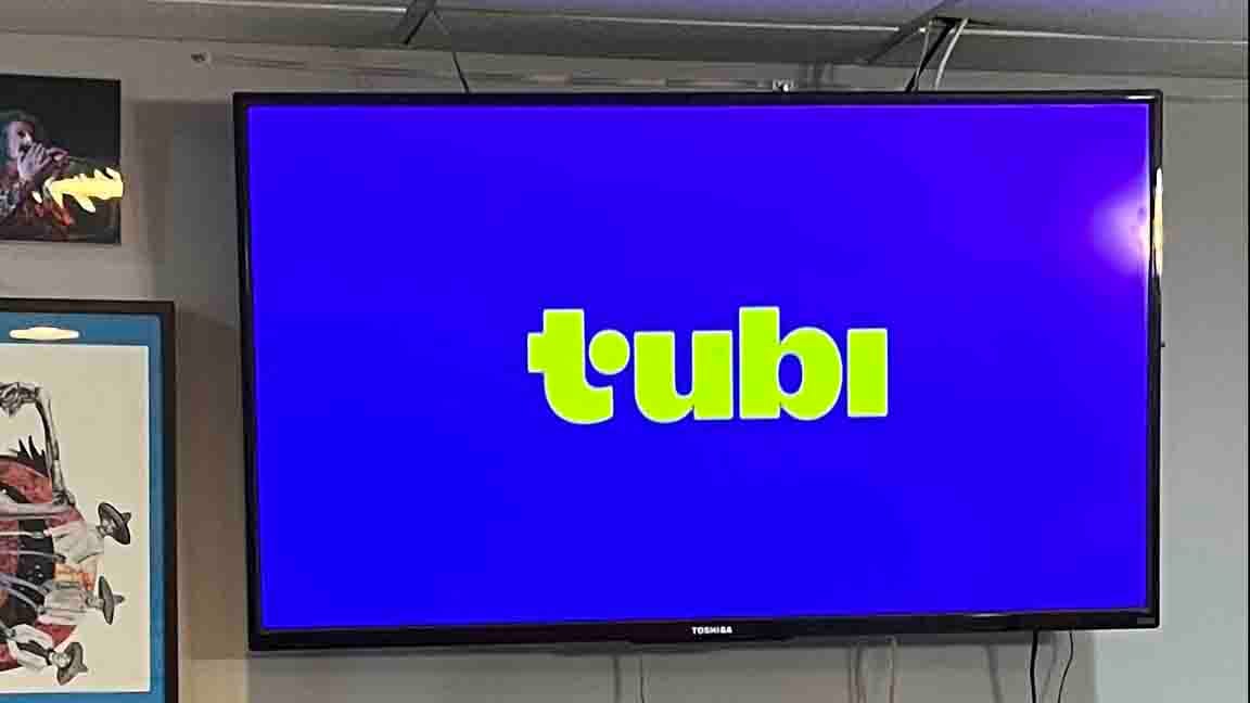 Bright blue startup screen for TUBI which reads "tubi" in greenish-yellow letters and there's no dit over the lowercase "i" but there's a dot on the right-hand crossmember of the lowercase "t" and I don't get it but it's a legit logo