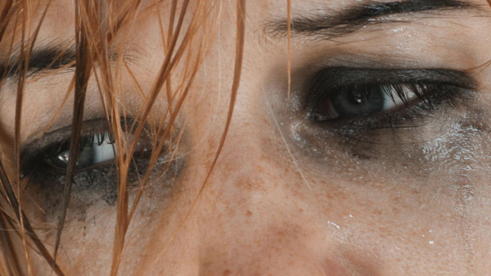 Closeup of weeping redhead's eyes with makeup running 