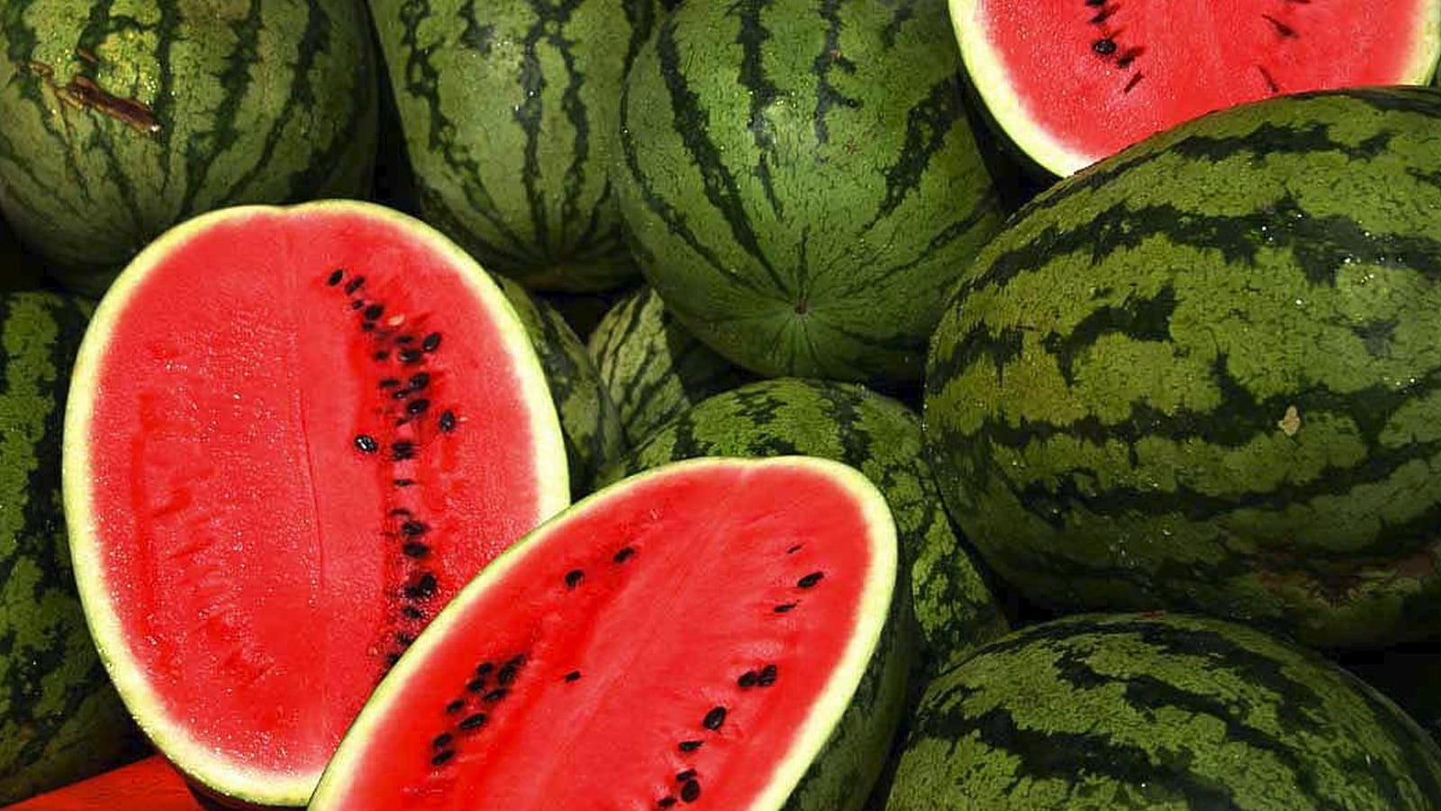 Some watermelons, some cut open, red, green and white