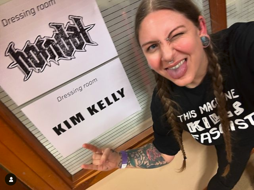 Kim Kelly pictured in front her her dressing room sign in Sweden, wearing a 'This Machine Kills Fascists' t-shirt!