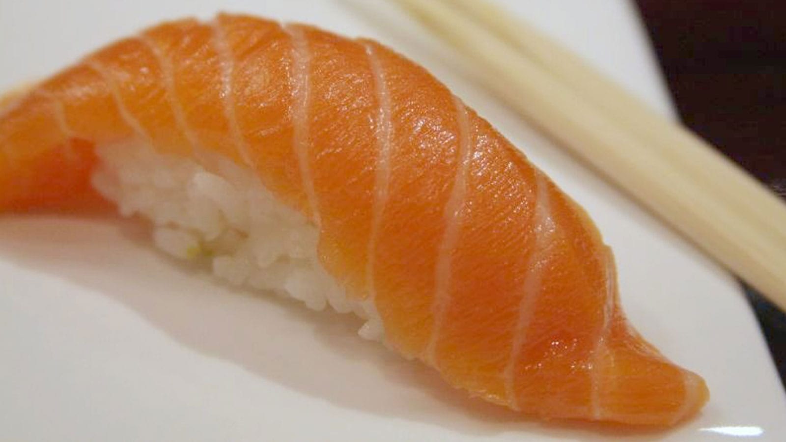 Luscious looking salmon nigiri on a white porcelain plate