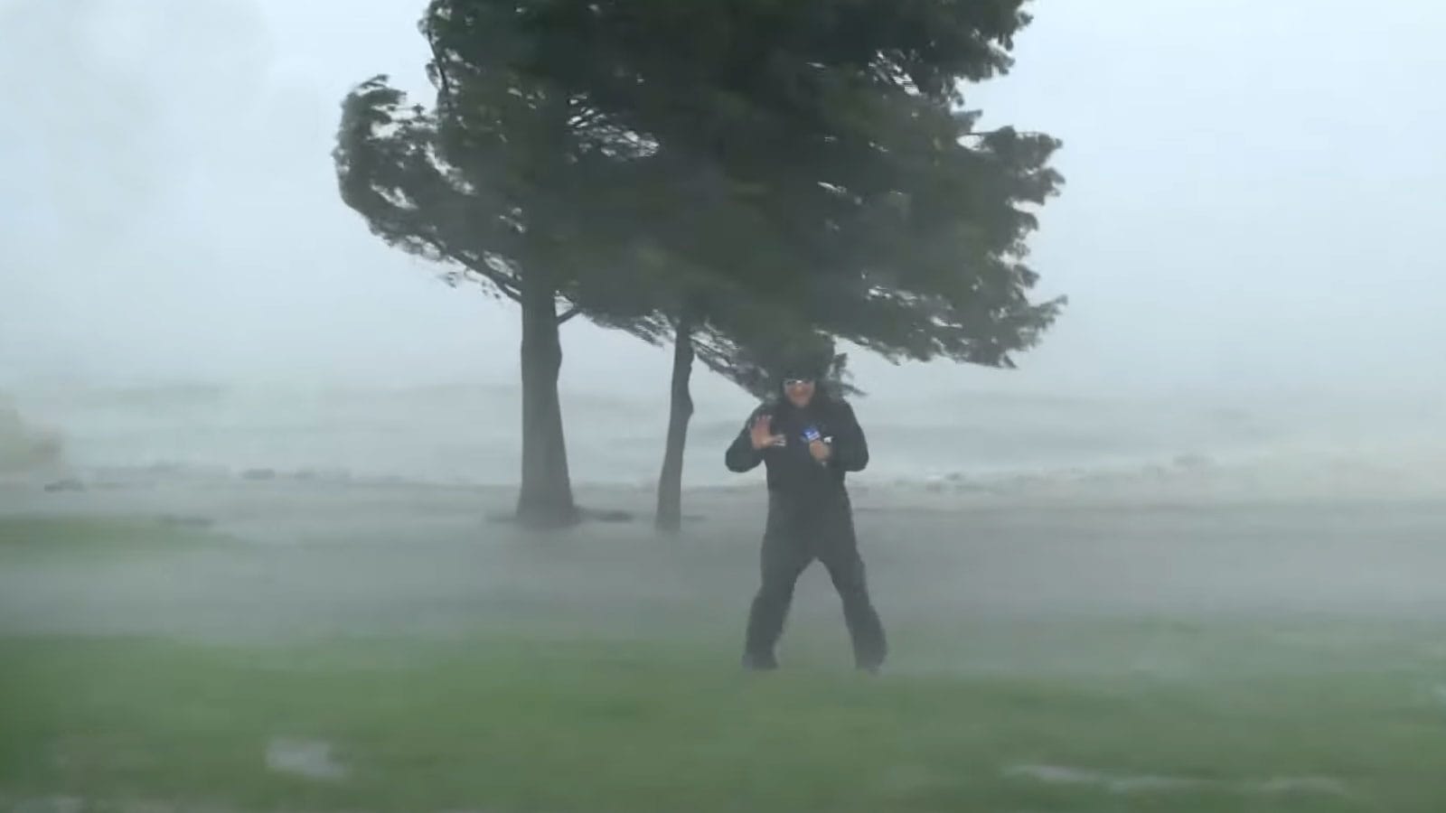 A screengrab from The Weather Channel shows a weather reporter struggling to stay upright in a hurricane