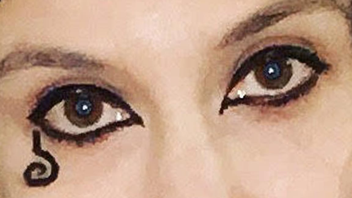 Extreme crop of photo in essay: Black-lined eyes and character-accurate black goth curly upside-down question-mark symbol drawn on cheekbone/corner of eye.