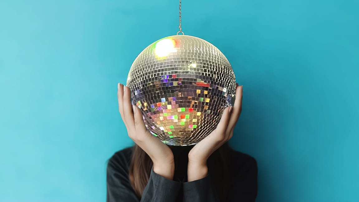 Photo illustration: Person holding their head in their hands but their head is a disco mirror ball.