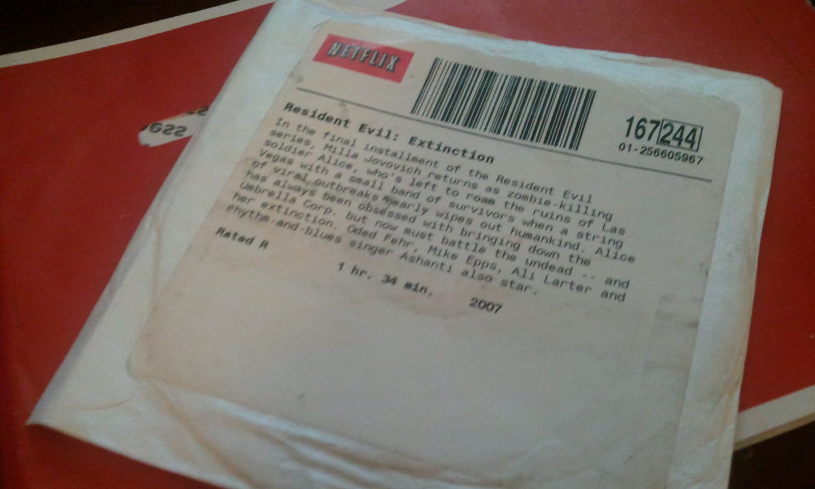 Barcoded paper Netflix sleeve for DVD rental of "Resident Evil: Extinction' (2007) and classic red Netflix postal envelope