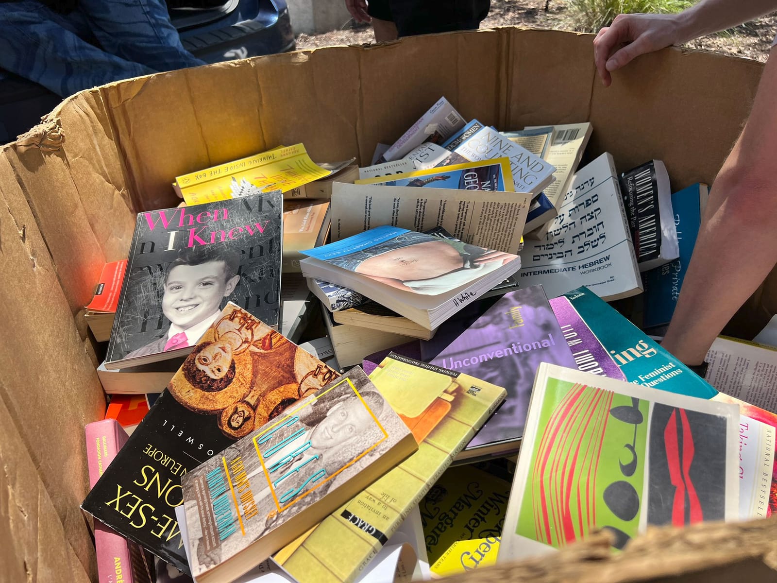 A pallet-sized cardboard box filled with colorful books and magazines in the Florida sun