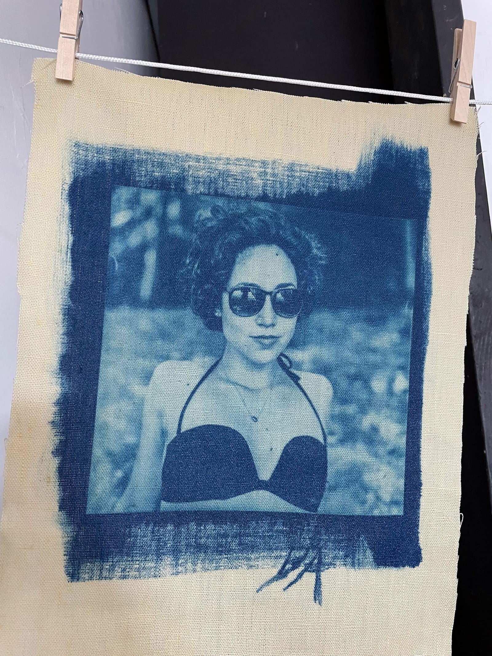 Cyanotype photo of the author, printed on canvas; she wears sunglasses, a bikini top and a pendant on a slender chain