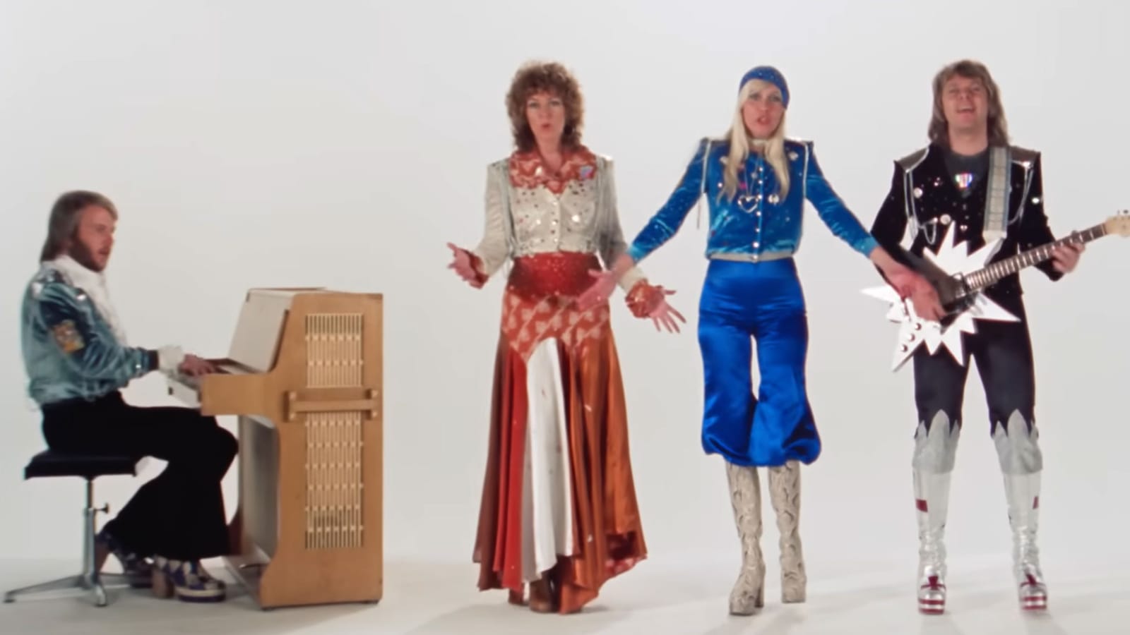 Screenshot ofthe four members of ABBA, performing in the music video for "Waterloo" in extremely colorful, shiny, sequined outfits and platform shoes